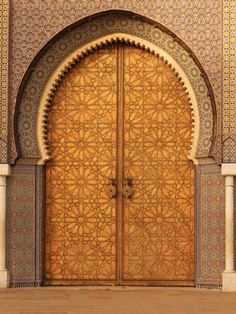 an intricately designed wooden door in the middle of a building with arches and doorways