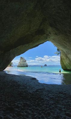 a person standing in the water under a cave