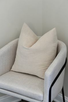 a chair with a pillow on top of it in front of a white wall and floor