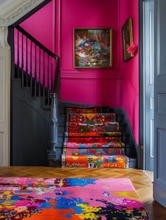 a staircase with bright pink walls and colorful rugs