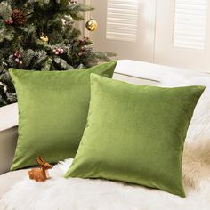 two green pillows sitting next to a christmas tree