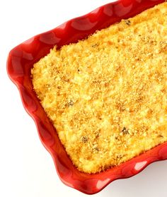 a red casserole dish filled with food on top of a white table