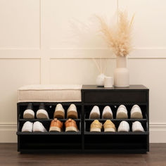 there are many pairs of shoes in the shoe rack on the floor next to a vase