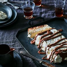 some food is laying out on a black tray with silverware and glasses next to it