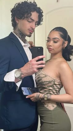 a man in a suit and tie standing next to a woman with tattoos on her chest