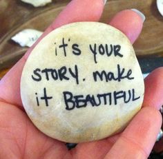 a person holding a rock with the words it's your story make it beautiful written on it