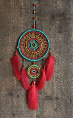 a red and blue dream catcher hanging on a wooden wall