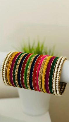 a stack of bracelets sitting on top of a white vase