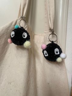 two black and white stuffed animals hanging from hooks on a door handle with a beige bag in the background