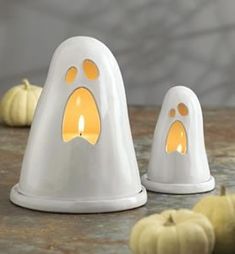 two white candlesticks with yellow paw prints on them and pumpkins in the background