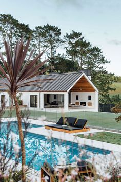 a house with a swimming pool in the foreground and a lounge chair next to it