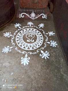 an artistic design on the ground in front of a brick wall and potted plant