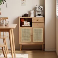 a small wooden table with two chairs and a cabinet in the corner next to it