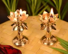 two brass candles sitting on top of a wooden table