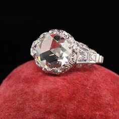 an old cut diamond ring sitting on top of a red velvet covered apple with black background