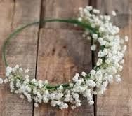 a white flower headband is laying on a wooden surface with green ribbon around it