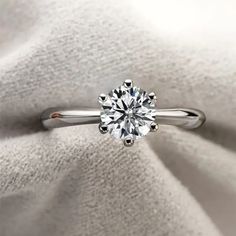 a white diamond ring sitting on top of a cloth