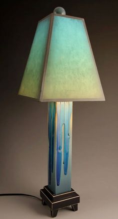 a lamp that is sitting on top of a wooden stand with a blue and green shade