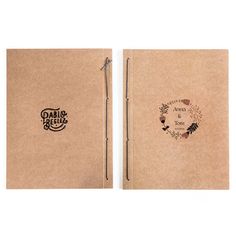 two brown notebooks sitting side by side on top of each other, one with a pen in it