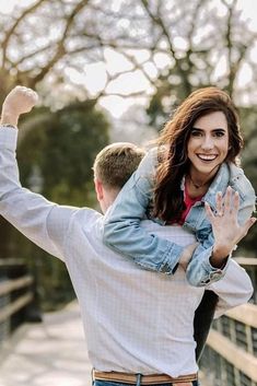 a man carrying a woman on his back while she is holding her in the air