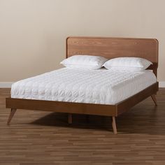 a bed sitting on top of a hard wood floor next to a white wall in a bedroom