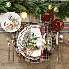 a place setting with plaid table cloth, silverware and evergreen branches on the plate