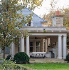 a large house with columns and an outdoor kitchen on the front porch is surrounded by greenery