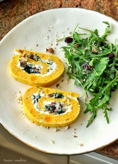 some food is sitting on a white plate with greens and other things to eat in front of it