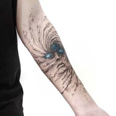 a man with a tattoo on his arm has a blue eyeball in the center