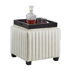 a white and black cooler sitting on top of a table next to a glass bottle