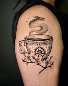 a woman with a tattoo on her arm has a cup of coffee and a dragon