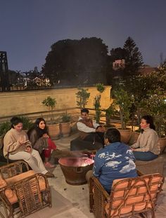 several people sitting around a fire pit at night