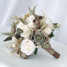 a bridal bouquet with white flowers and greenery on a white tablecloth background