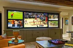 a living room filled with lots of furniture and large tvs on the wall above them