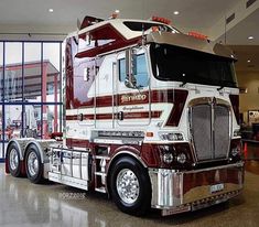 a large semi truck is parked in a building with glass doors and windows behind it