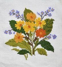 a cross stitched picture of flowers on a white cloth with blue and yellow leaves