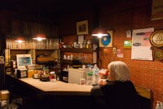 a woman sitting at a bar in front of a brick wall