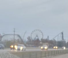 cars driving down the road in front of an amusement park