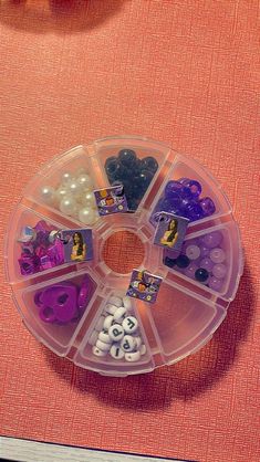 a plastic container filled with lots of different types of buttons and beads on top of a table