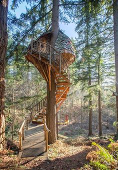 a wooden tree house in the woods with stairs leading up to it's roof