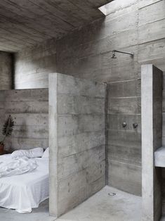 an instagram photo of a bed and shower in a room with concrete walls on the wall