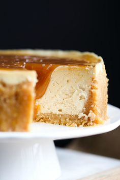 a piece of cheesecake with caramel topping on a white cake plate, ready to be eaten