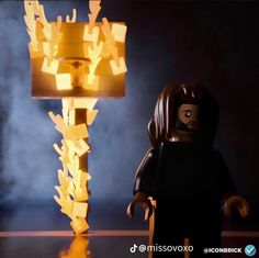 a lego figure is standing next to a lamp with flames coming out of the top