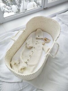 a white knitted baby's cradle in front of a window with snow outside