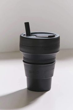 a black coffee cup sitting on top of a white table