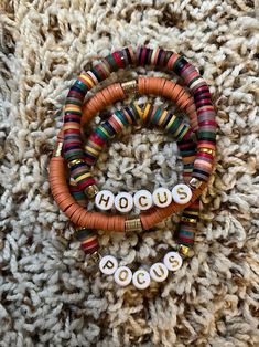 three bracelets with beads on top of a pile of carpeted wool and the words hoocu spelled out in white letters