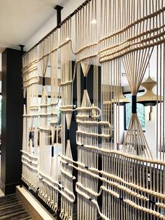 a room divider made out of bamboo sticks and ropes with lamps in the background