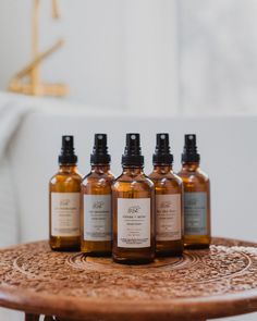 five bottles of liquid sitting on top of a wooden table