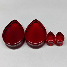 three red glass pieces sitting next to each other on a white surface with space for text