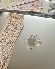 an open laptop computer sitting on top of a wooden table next to other stickers